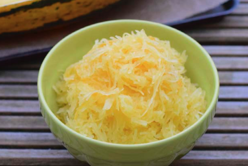 1 bowl of roasted spaghetti squash on a wooden table.