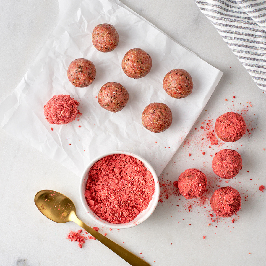 7 pink Beet balls on top of white napkin beside another 4 pink Beet balls on the table top surface  beside a bowl of pink mixture and a golden spoon.